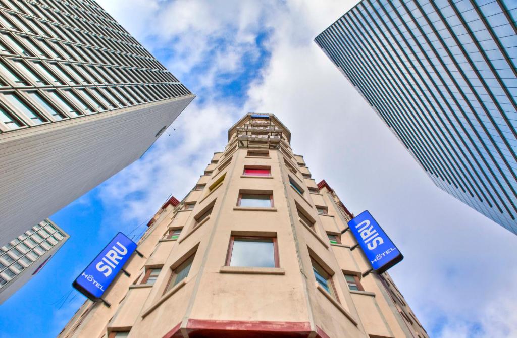 Un edificio alto con dos signos azules. en Hotel Siru en Bruselas