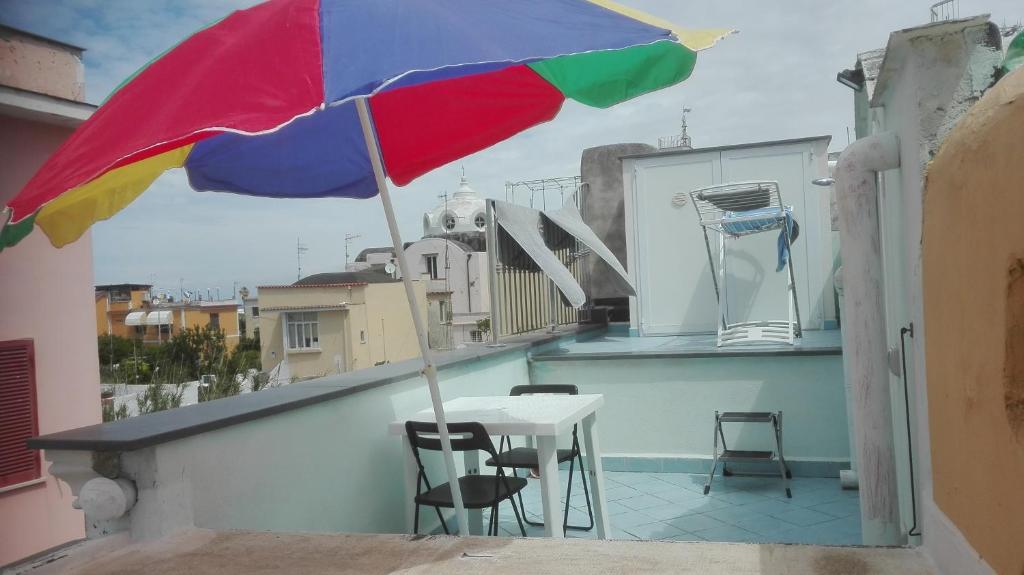 a colorful umbrella on a balcony with a table and chairs at Casa Cucurullo in Procida