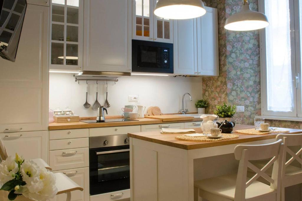 una cucina con armadi bianchi e tavolo con sedie di Flowers Apartment ALTIDO 25 a Como