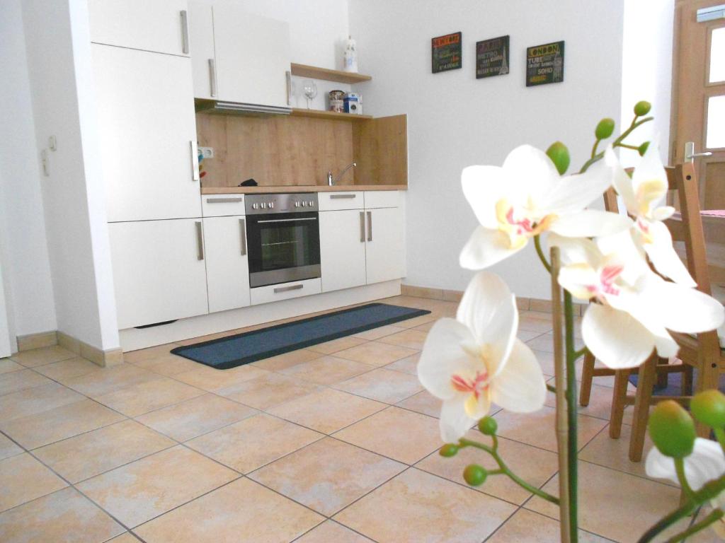 a kitchen with white cabinets and white flowers at Apartments Altstadtflair in Regensburg