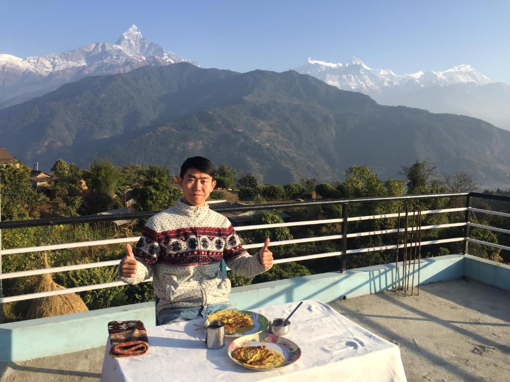 un hombre sentado en una mesa con dos platos de comida en KB'S ECO MOUNTAIN VILLAGE HOME, en Kāskī