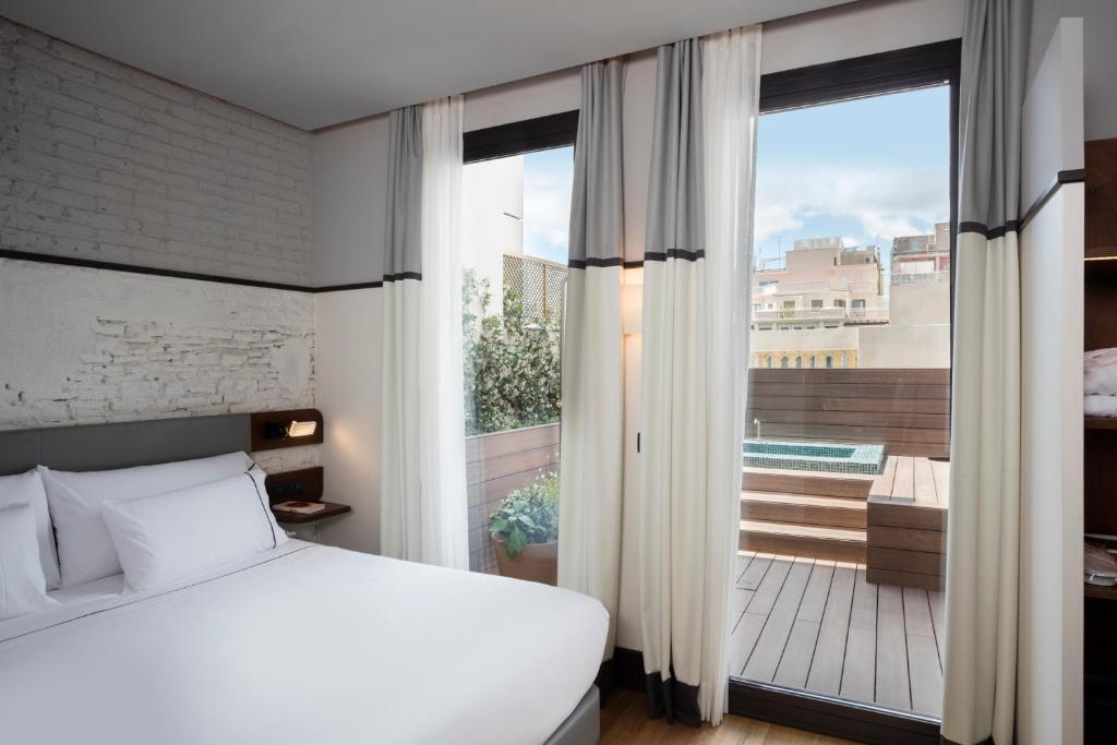 1 dormitorio con cama y vistas a un balcón en Praktik Èssens, en Barcelona