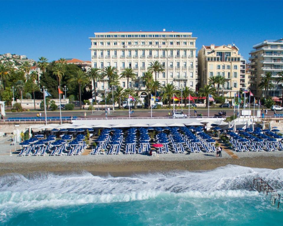 a beach with blue chairs and a building at Hôtel West End Promenade in Nice