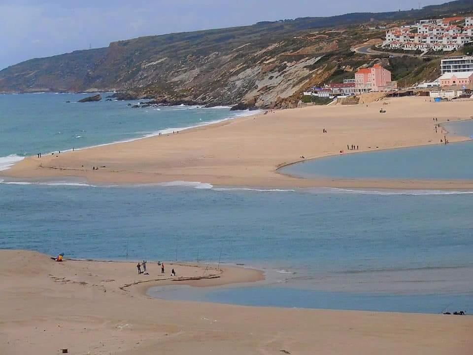 a group of people on a beach near the water at O Facho Guest House in Foz do Arelho