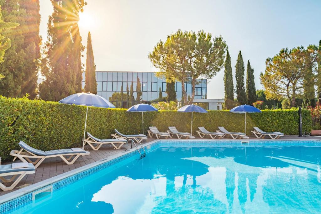 a swimming pool with chairs and umbrellas at Residence Nuove Terme in Sirmione