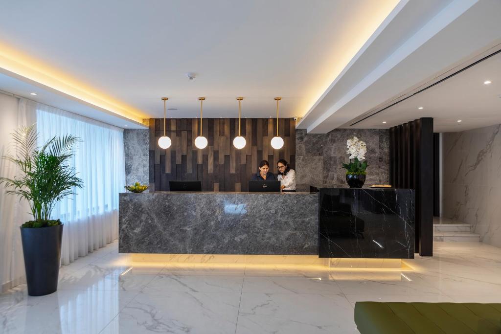 two people standing at a counter in a lobby at Leonardo Crystal Cove Hotel & Spa – Adults only in Protaras