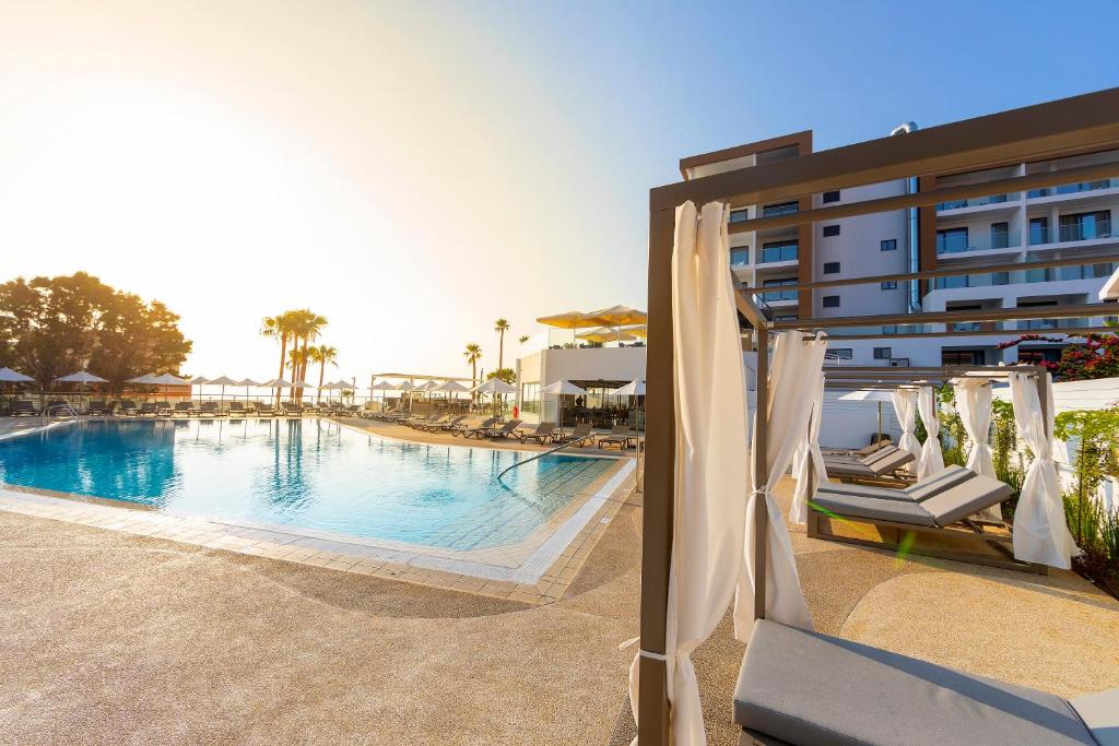 a swimming pool with chairs and a building at Leonardo Crystal Cove Hotel & Spa – Adults only in Protaras
