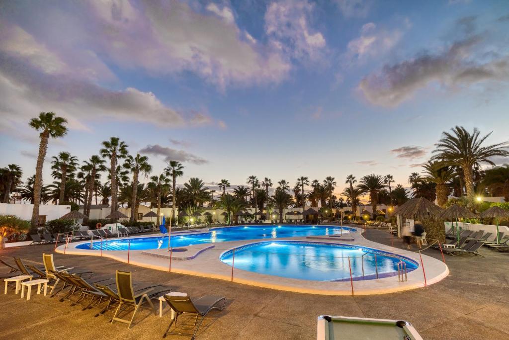 a large swimming pool with chairs and palm trees at Ona Las Brisas in Playa Blanca