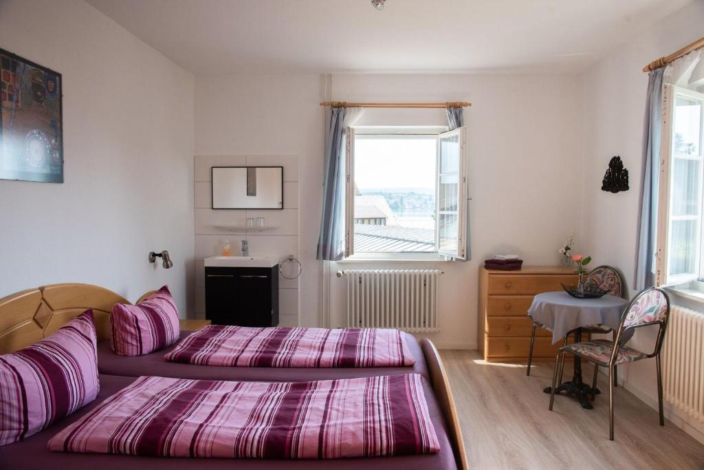 1 dormitorio con 2 camas, mesa y ventana en Ferienwohnungen Richard Wurz, en Reichenau