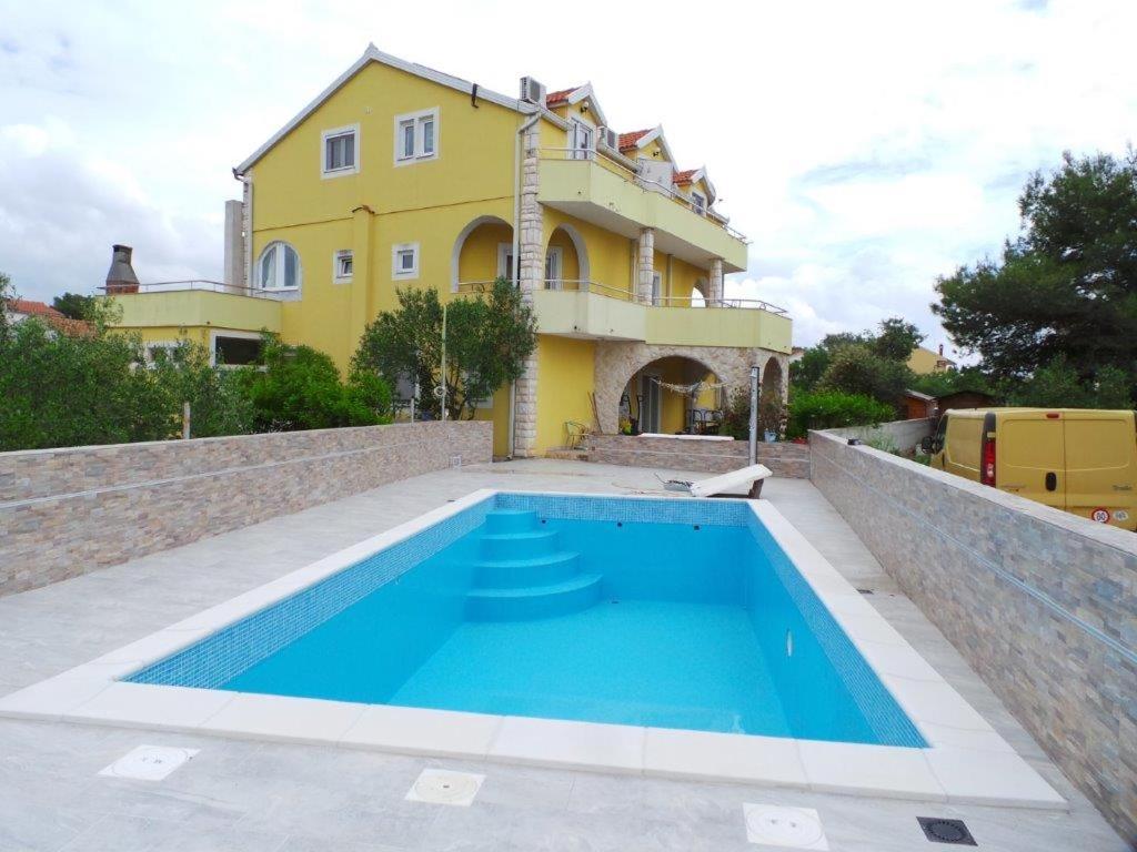 a villa with a swimming pool in front of a house at Apartments Ankica in Šibenik