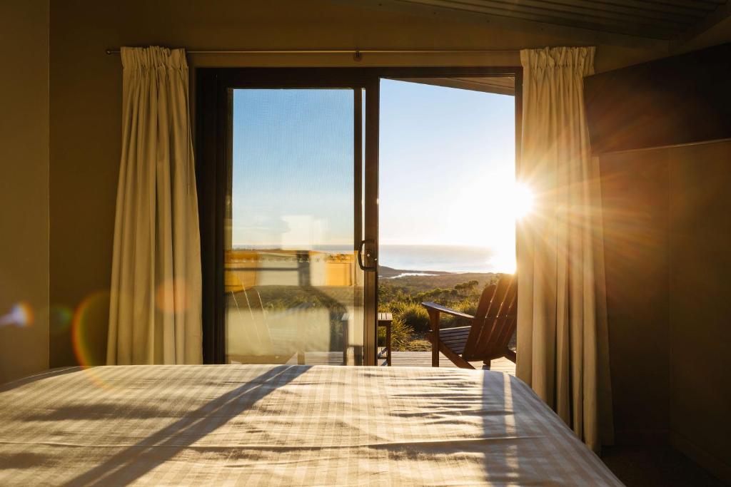 a bedroom with a bed and a window with the sun at Freycinet Resort in Coles Bay