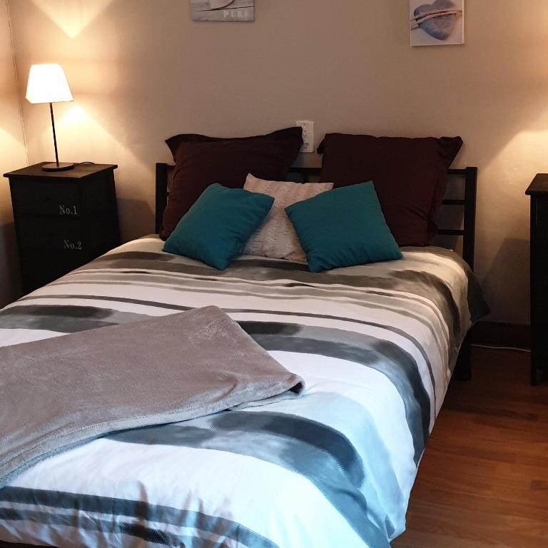 un lit avec deux oreillers bleus dessus dans l'établissement le gite du baron, à Roz-sur-Couesnon