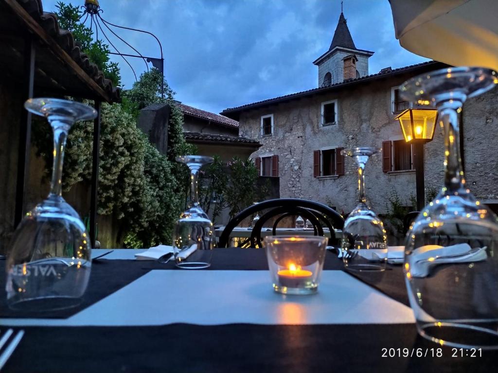 uma mesa com copos de vinho e uma vela em Il torchio antico em Arzo