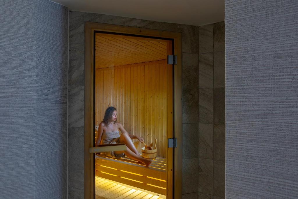 a woman sitting on a window sill in a room at Leonardo Crystal Cove Hotel & Spa – Adults only in Protaras