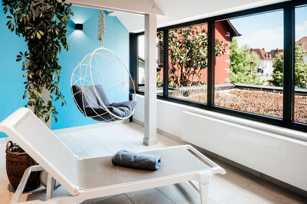 a living room with a white bench and a large window at Logis Hôtel Restaurant Au Lion Rouge in Bartenheim