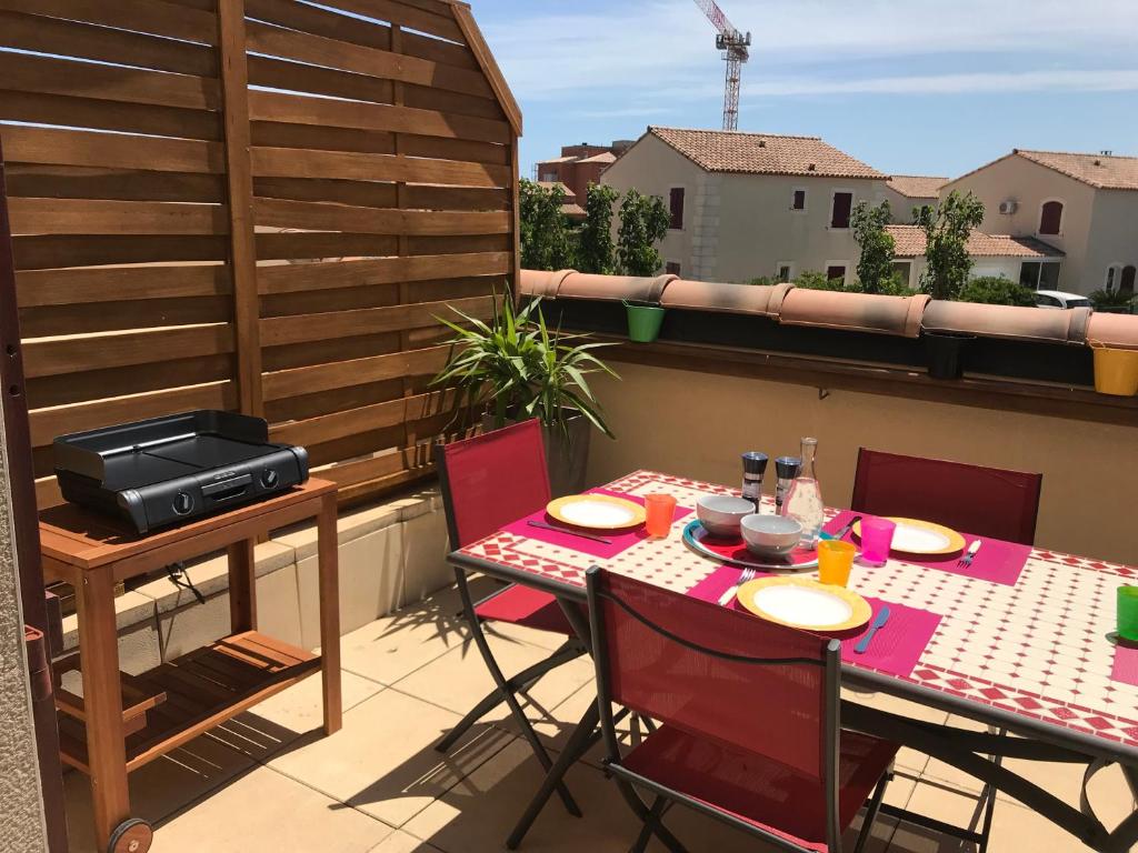 d'une terrasse avec une table et des chaises sur un balcon. dans l'établissement Grandes Bleues, Appartement T3 duplex, piscine, Narbonne Plage, à Narbonne-Plage