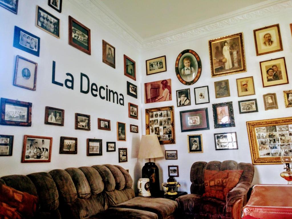 una sala de estar con 2 sofás y una pared de cuadros. en La Decima Guest House, en Chihuahua