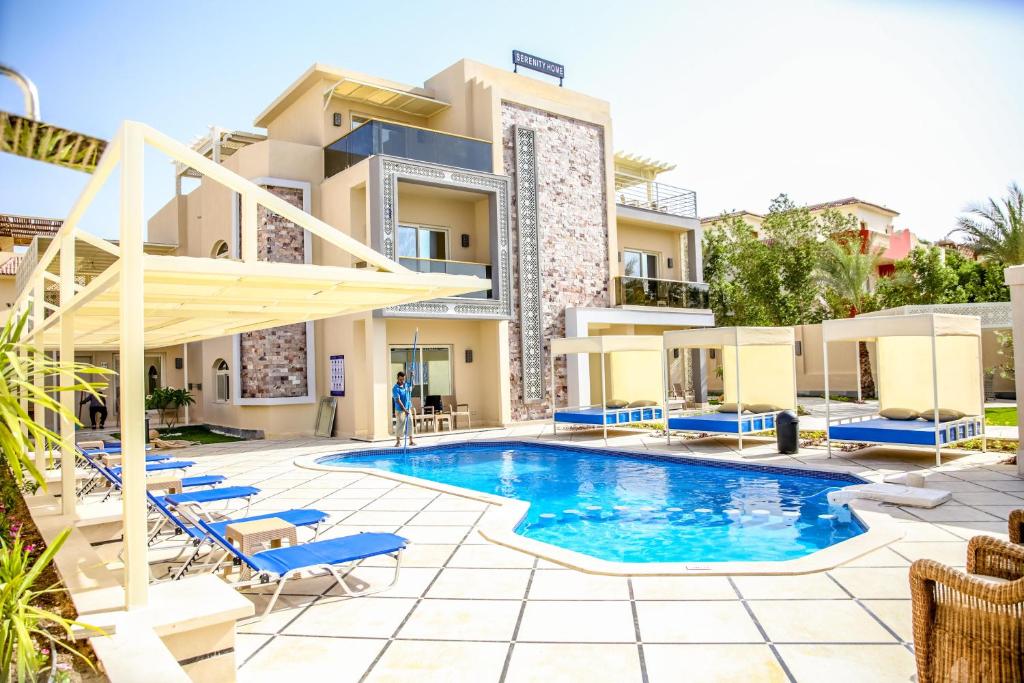 uma piscina em frente a um edifício com espreguiçadeiras azuis em Serenity Home Hurghada em Hurghada