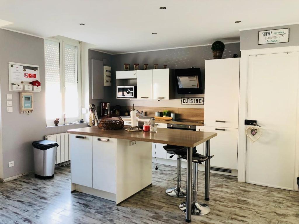 une cuisine avec des placards blancs et une table en bois dans l'établissement Maison de ville à Albert, à Albert