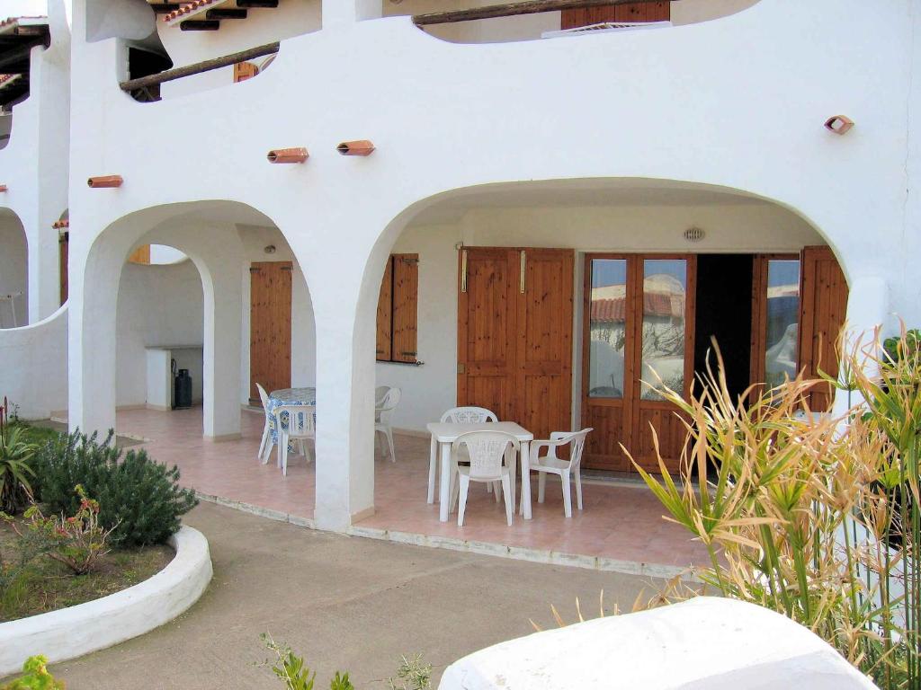 a white house with a patio with a table and chairs at Valledoria holiday flats in Valledoria