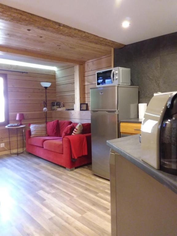 - un salon avec un canapé rouge et un réfrigérateur dans l'établissement le Woody, à Saint-Étienne-de-Tinée