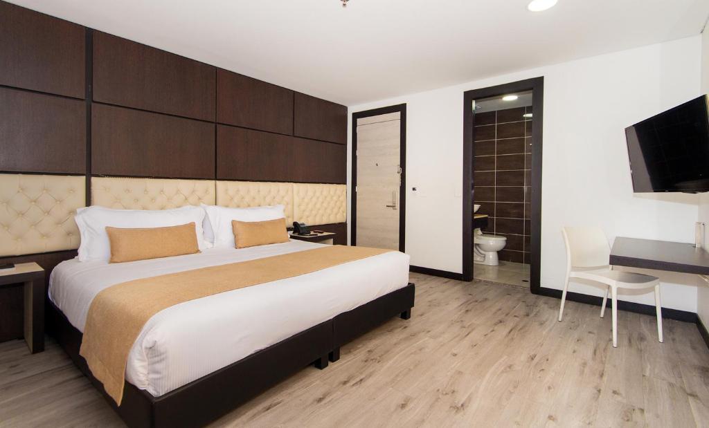 Dormitorio con cama, escritorio y TV en Hotel American Visa Tower, en Bogotá