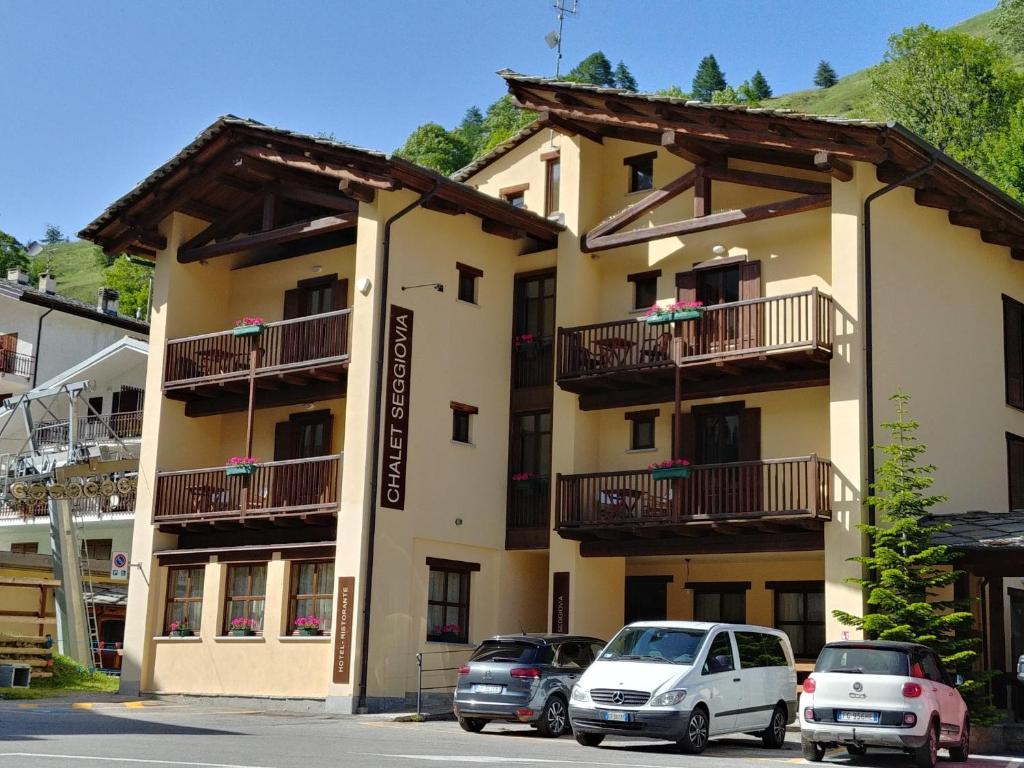 un edificio con auto parcheggiate di fronte di CHALET SEGGIOVIA a Pontechianale