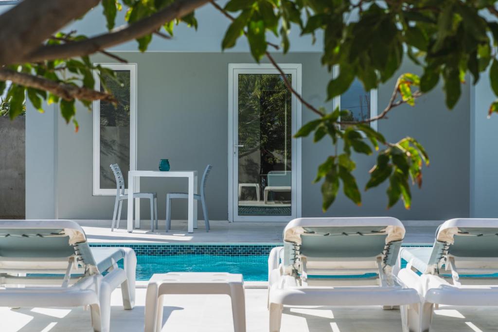 two lounge chairs and a swimming pool with a house at Hideout Suites - from Eagle Beach in Palm-Eagle Beach