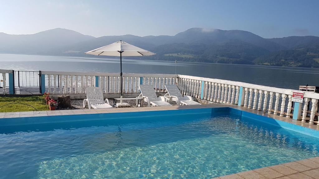 a swimming pool with chairs and an umbrella and water at Casa Yuppy Du in Eşelniţa