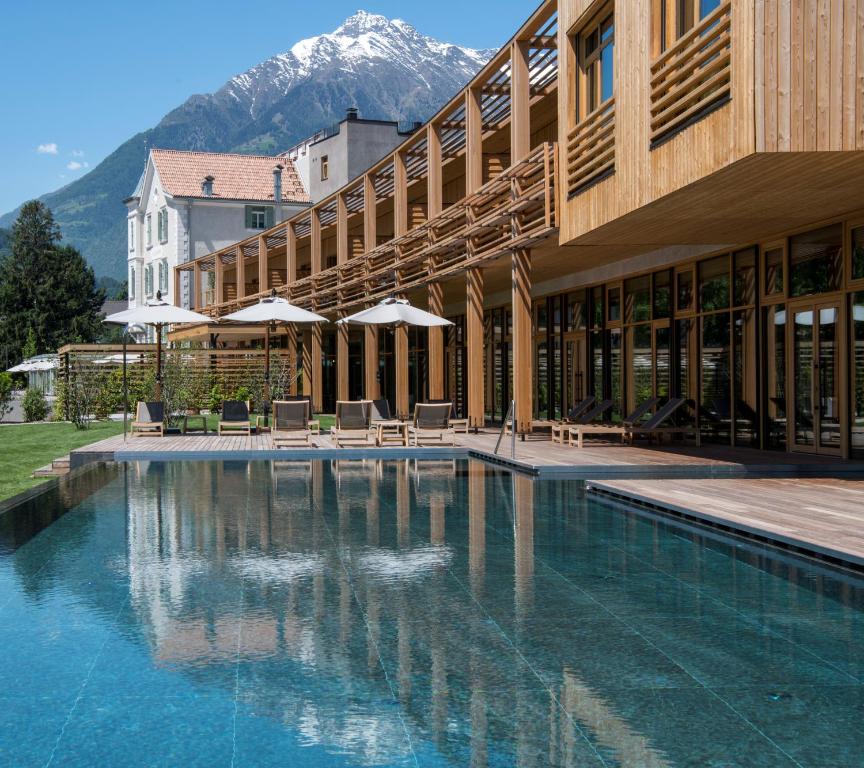 a swimming pool in front of a building with a mountain at VillaVerde Aparthotel in Lagundo