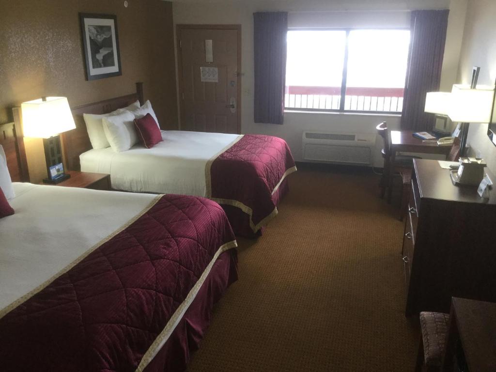 a hotel room with two beds and a desk at Baymont by Wyndham Cortez in Cortez