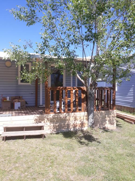 a house with a porch with a bench and a tree at mobil home paradisiaque in Crots