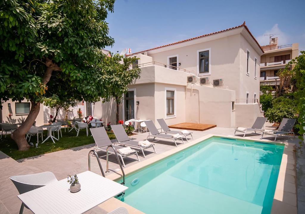 a swimming pool with chairs and a table and a house at Epavli Boutique Hotel in Chania Town