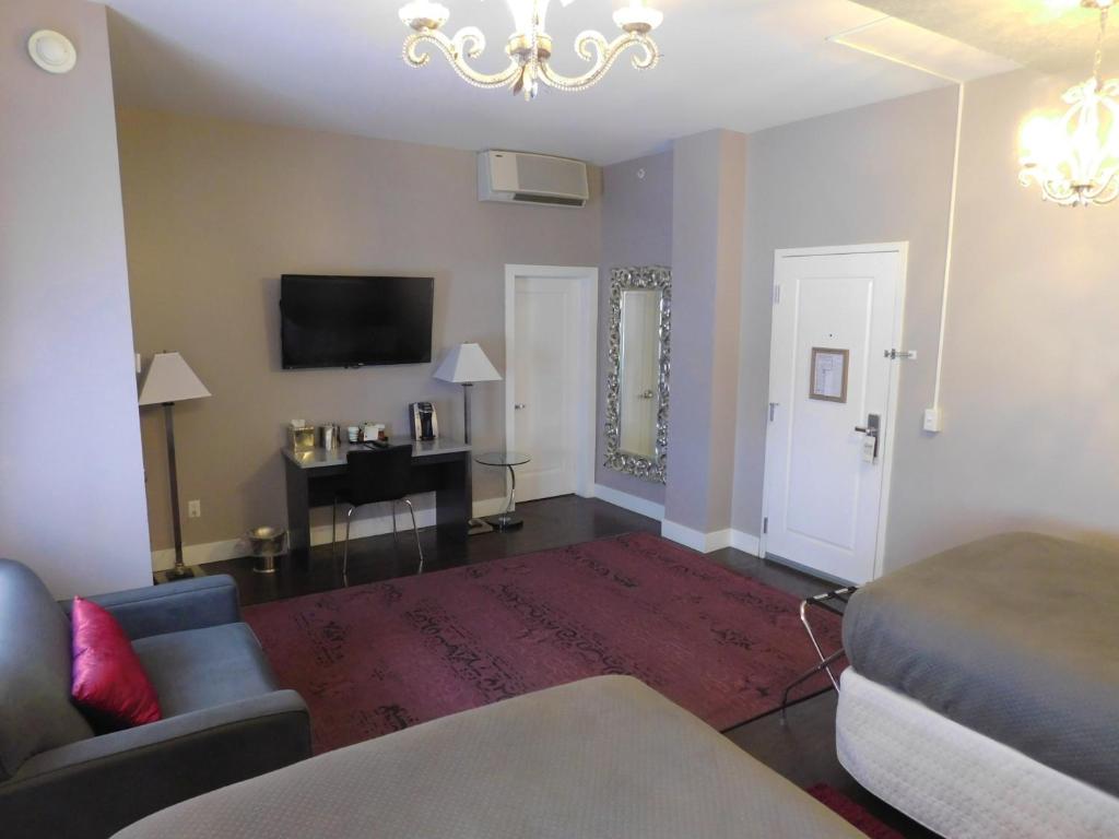 a living room with a couch and a tv at The Gould Hotel in Seneca Falls