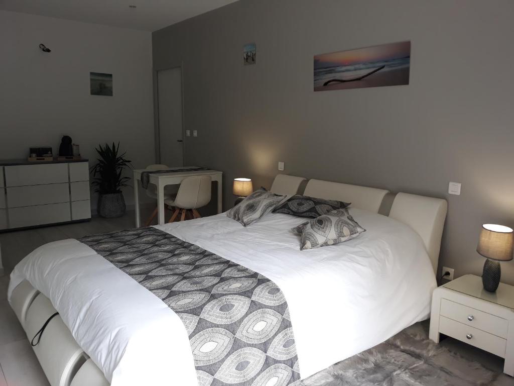 a bedroom with a white bed and a table at Chambre d'hôtes du Pin in Pey