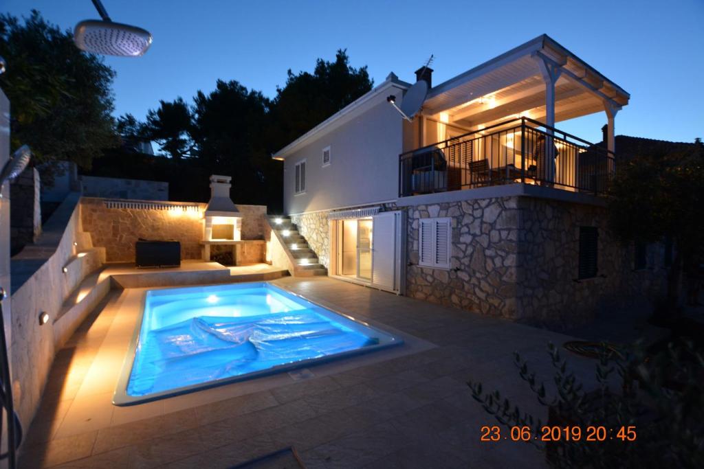a swimming pool in front of a house at night at Sealodge - Luxe Villa, private pool, mooring, parking, sea & mountain view, at 150 m from idyllic private beach in Rogač