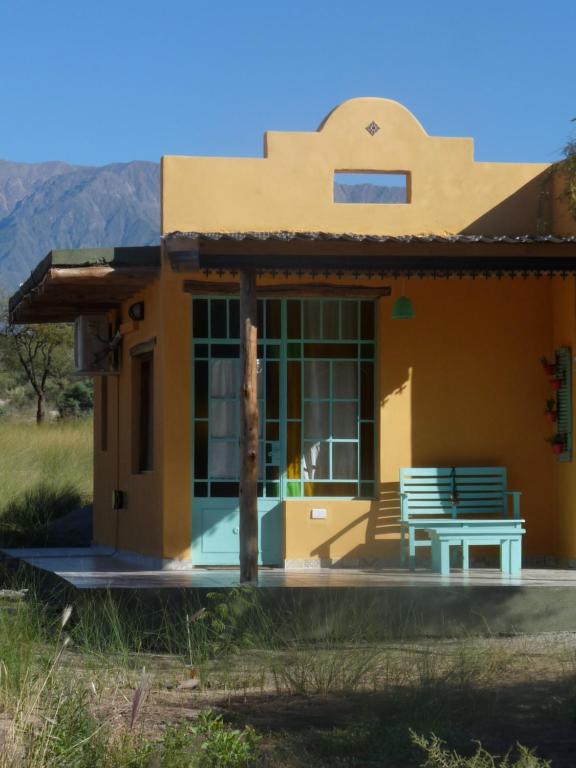 una pequeña casa amarilla con un banco delante en Los Remenizos Cabañas de Montaña en Belén