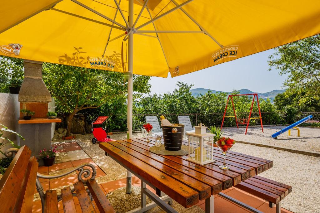 a wooden table with an umbrella and a playground at Apartments Josip in Trogir