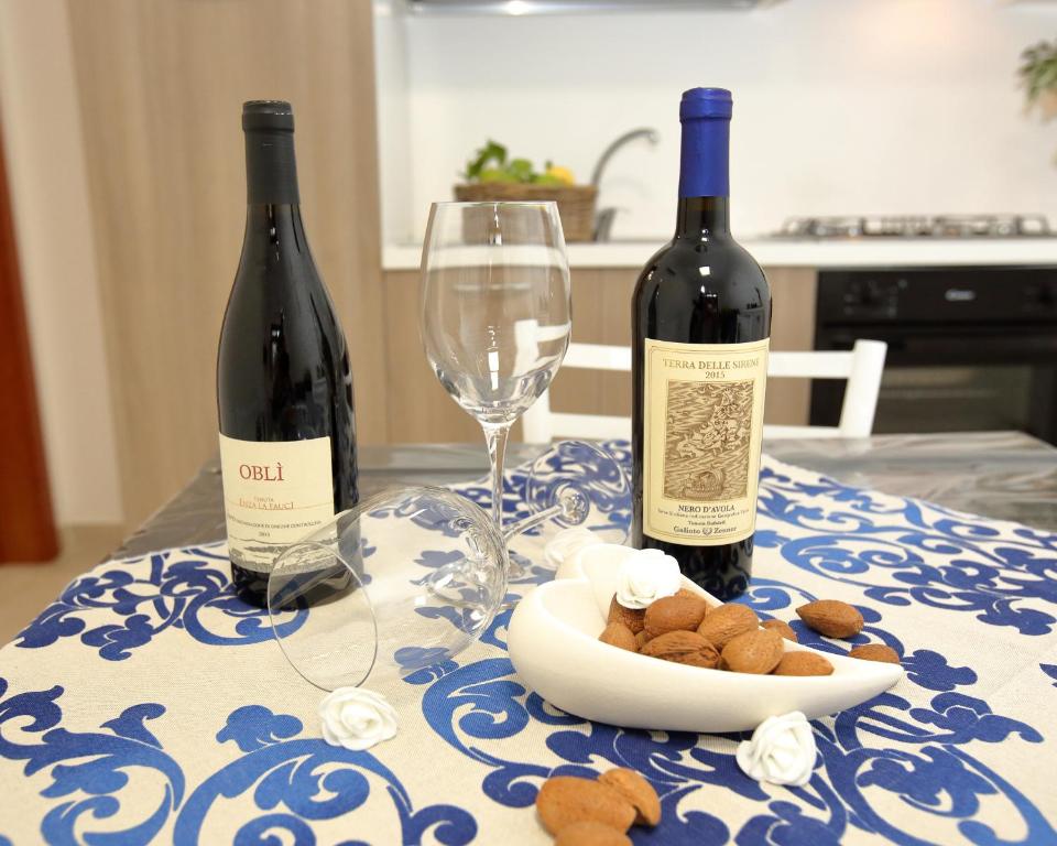 アヴォラにあるLa casa di Cristinaのワイン2本、テーブルの上に食べ物の盛り合わせ