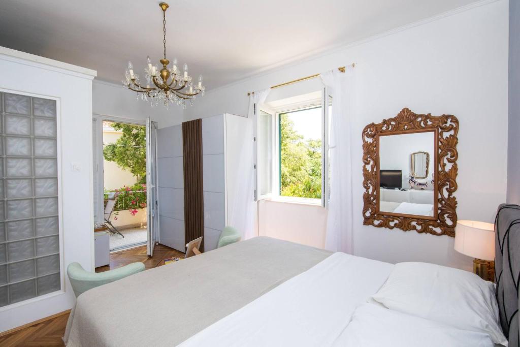 Habitación blanca con cama y espejo en Lapad House, en Dubrovnik