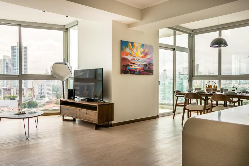 ein Wohnzimmer mit einem TV und einem Tisch mit Stühlen in der Unterkunft All Mode City View Apartment - PH Quartier Del Mar in Panama-Stadt
