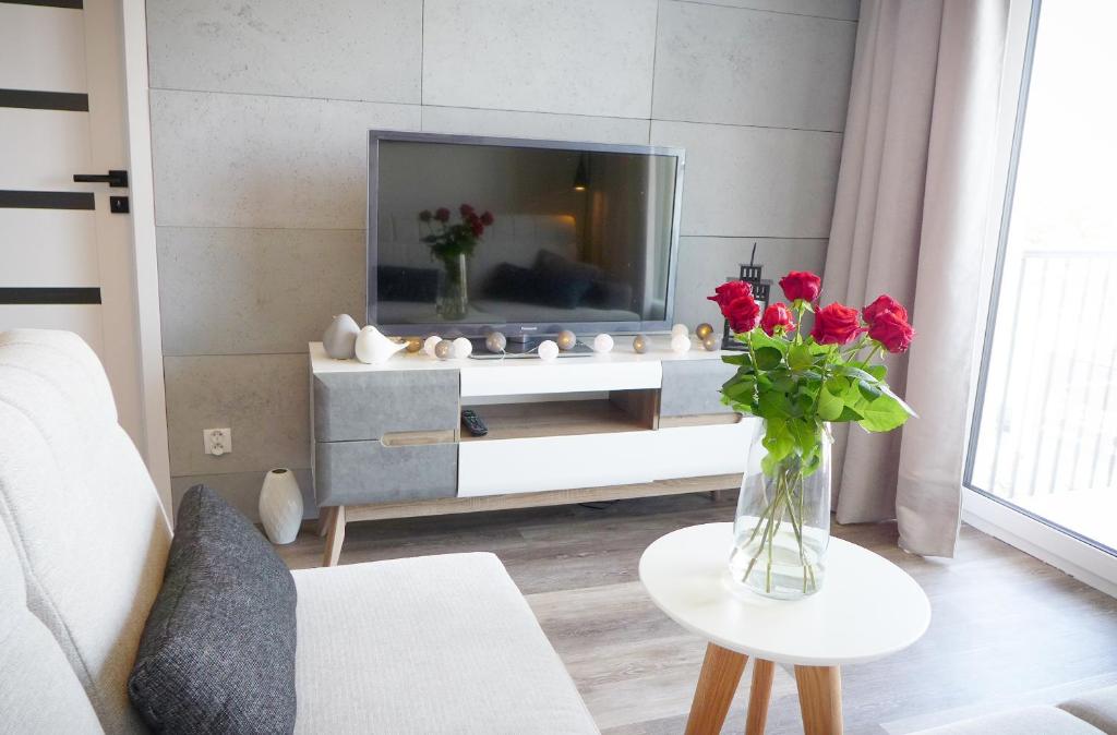 een woonkamer met een vaas met rode rozen op een tafel bij Apartament Blue Paradise in Kołobrzeg