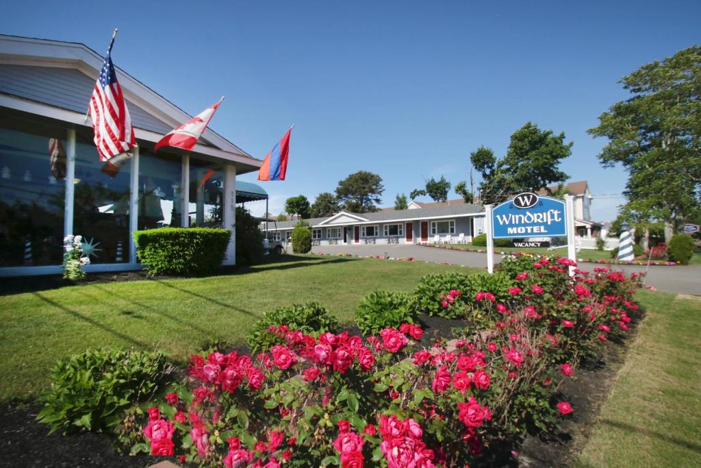 a building with a flag and flowers in front of it at Windrift Motel in West Yarmouth