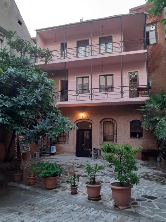 un bâtiment rose avec des plantes devant lui dans l'établissement Hotel Zaira, à Tbilissi