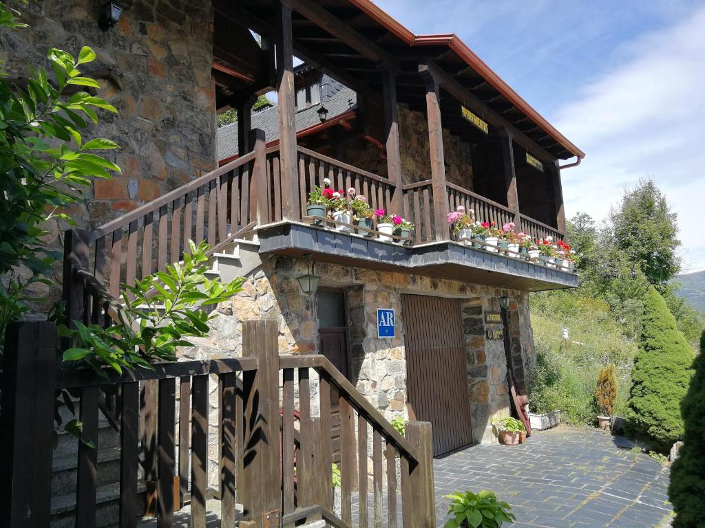 a building with a balcony with flowers on it at Alojamientos Rurales El Fontano in Galende