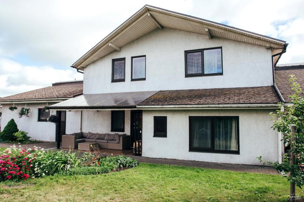 a white house with black windows and a yard at Flower apartment in Ventspils
