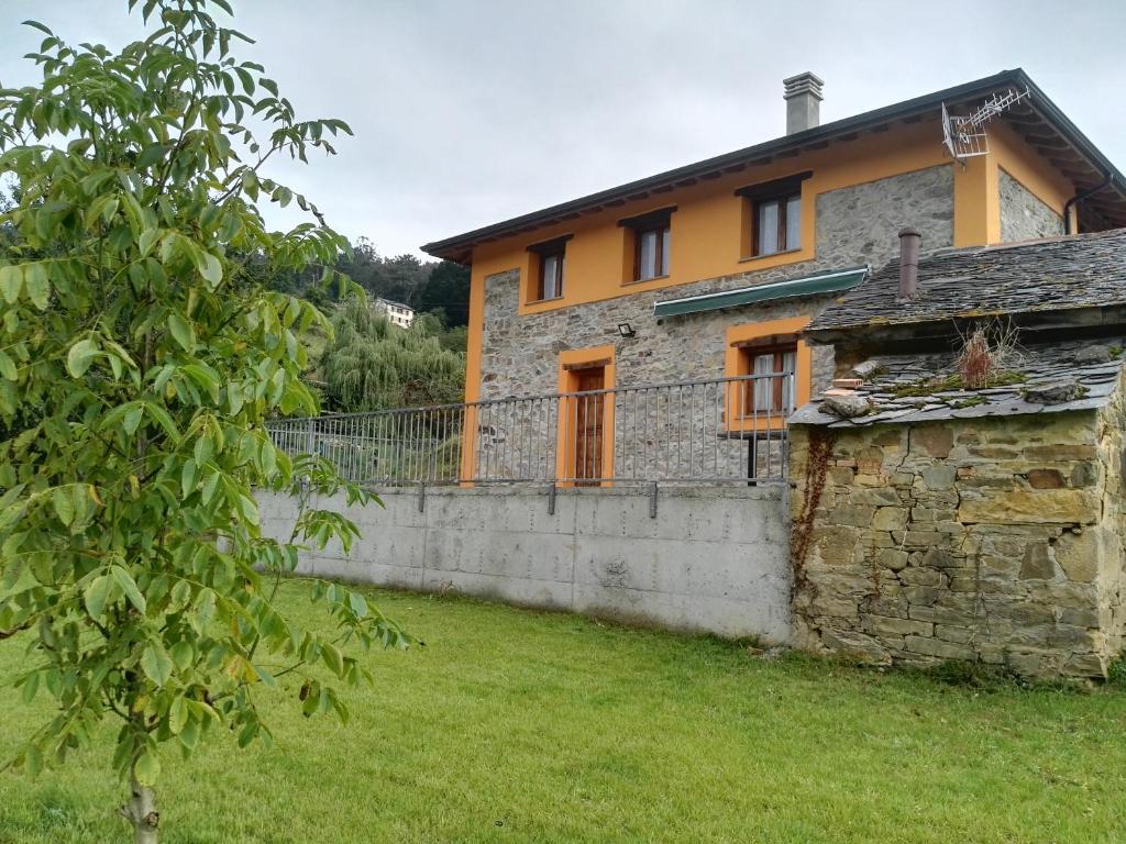 una vieja casa de piedra con una pared y un patio en Casa el Fanoso, en Luarca