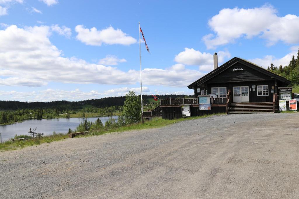 un edificio con una bandera al lado de una carretera en Gamlestølen Fjellstue, en Etnedal