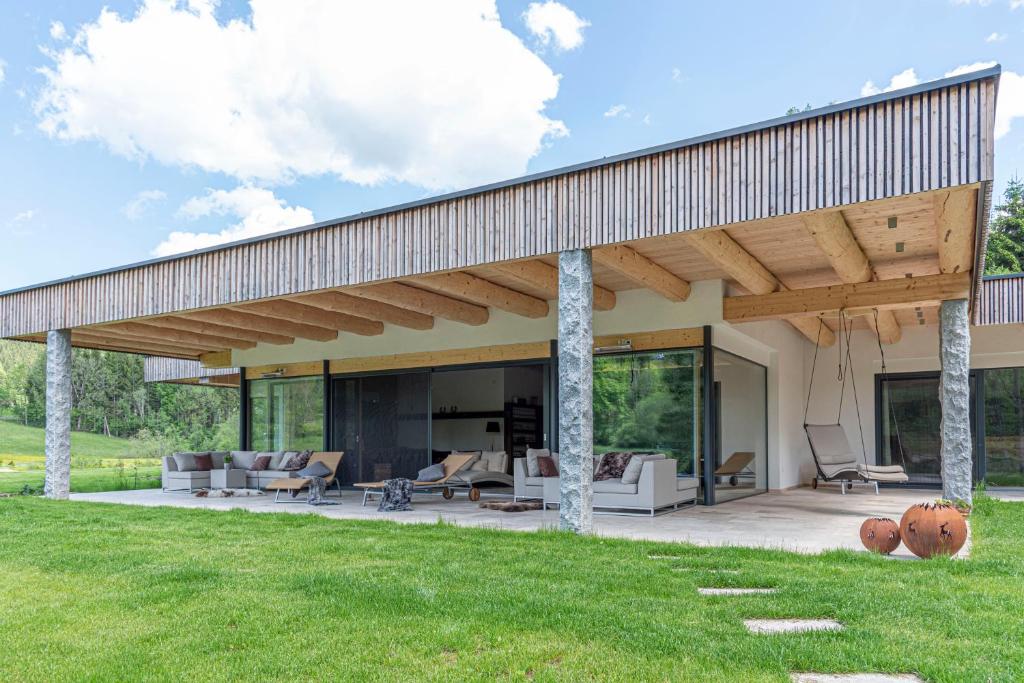 a modern house with acovered patio with furniture at Ferienhaus am See mit Sauna und Whirlpool in Wienerbruck