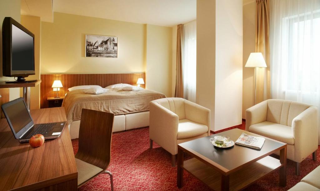 a hotel room with a bed and a desk and chair at Clarion Congress Hotel České Budějovice in České Budějovice